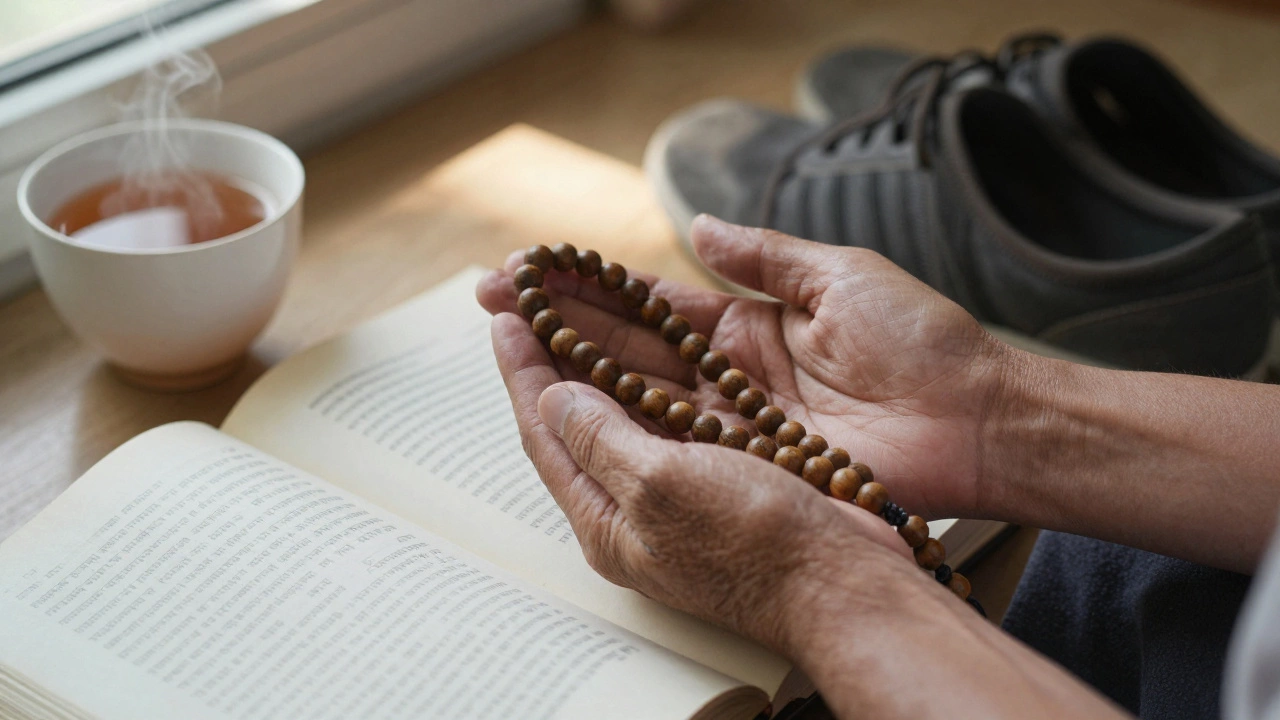 Weathered hands holding a mala necklace beside an open yoga text and tea.